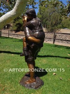 Piggyback bronze statue of boy carrying young girl on his back