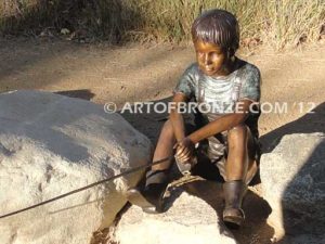 Fish n Hole bronze sculpture of young boy sitting and fishing