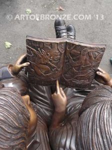 Friendship bronze sculpture of young girl and boy sitting on bench looking at book