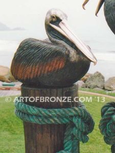 Taking a Break bronze statue of playful pelicans on bronze pilings