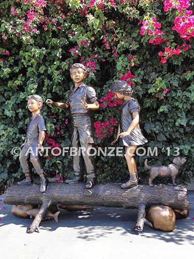 Young Adventurers bronze sculpture of children playing on fallen bronze tree
