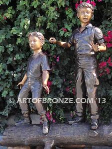 Young Adventurers bronze sculpture of children playing on fallen bronze tree