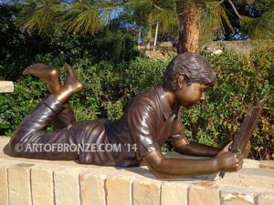 Best in His Class side view bronze statue of boy lying down reading book