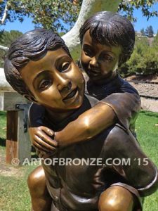 Piggyback bronze statue of boy carrying young girl on his back