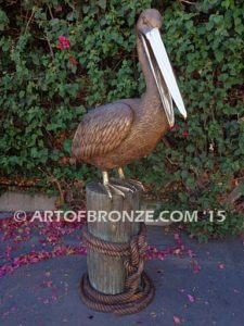 Pelican Perch bronze statue of playful pelican on bronze piling