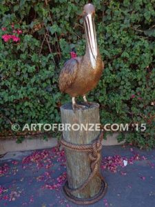 Pelican Perch bronze statue of playful pelican on bronze piling