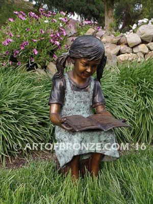 High Achiever bronze sculpture of girl wearing dress with pigtails sitting on log reading book