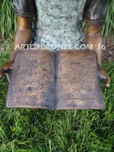 High Achiever bronze sculpture of girl wearing dress with pigtails sitting on log reading book