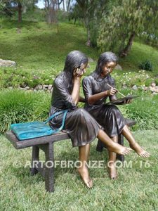 Big Sister side view B bronze statue of two girls sitting on bench drawing