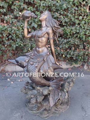 Bronze sculpture of mermaid blowing conch shell pond, pool or aquatic display