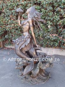 Bronze sculpture of mermaid blowing conch shell pond, pool or aquatic display