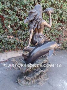 Bronze sculpture of mermaid blowing conch shell pond, pool or aquatic display