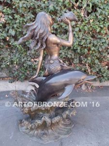 Bronze sculpture of mermaid blowing conch shell pond, pool or aquatic display