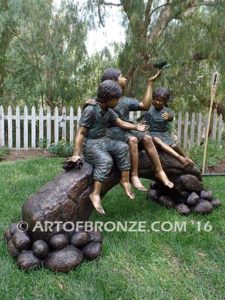 Butterfly Enchantment side view bronze sculpture of three kids sitting on log with butterfly net