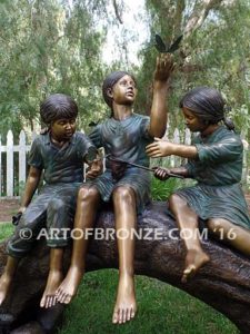 Butterfly Enchantment closeup A bronze sculpture of three kids sitting on log with butterfly net