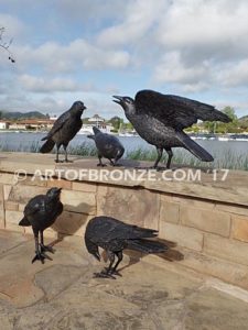 Raven bronze sculpture of ravens playing bench at lake