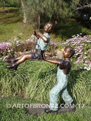 Push Me Higher bronze sculpture for park or playground of boy pushing girl on swing