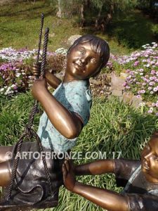 Push Me Higher bronze sculpture for park or playground of boy pushing girl on swing