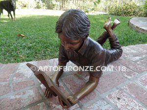 Best in His Class Sm closeup A bronze statue of boy lying down reading book