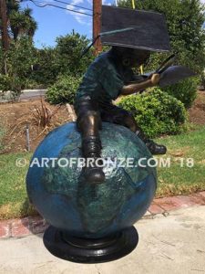 Global Scholar bronze sculpture of boy sitting on globe wearing graduation cap and reading book