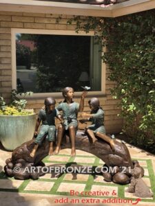 Butterfly Enchantment bronze statue of three children sitting on log playing with butterflies