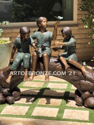 Butterfly Enchantment bronze statue of three children sitting on log playing with butterflies