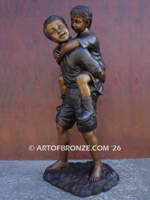 Piggyback bronze statue of boy carrying young girl on his back