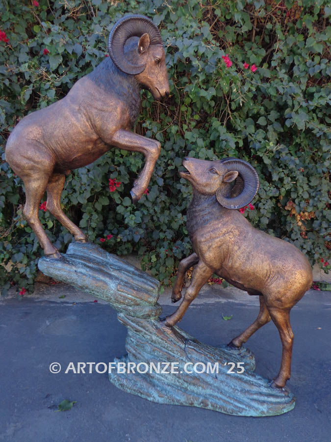 Clash of the Titans outdoor bronze sculpture of two fighting big horn sheep fighting on bronze rock ledge