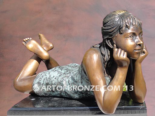 Day Dreaming bronze statue of relaxing girl lying down on stomach