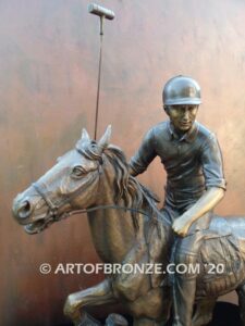 Downfield bronze sculpture of polo player riding his leaping polo pony attached to a marble base