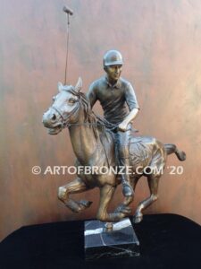 Downfield bronze sculpture of polo player riding his leaping polo pony attached to a marble base