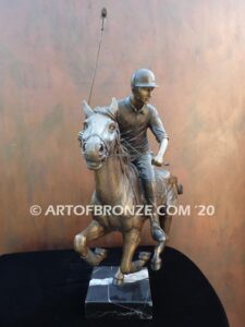 Downfield bronze sculpture of polo player riding his leaping polo pony attached to a marble base