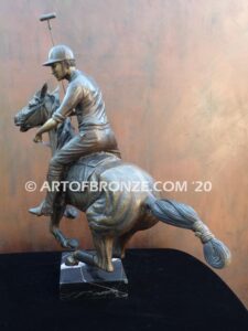 Downfield bronze sculpture of polo player riding his leaping polo pony attached to a marble base