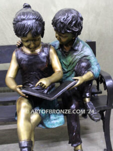 Friendship outdoor bronze garden sculpture of two children reading a book on bench