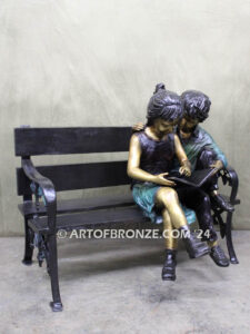 Friendship outdoor bronze garden sculpture of two children reading a book on bench