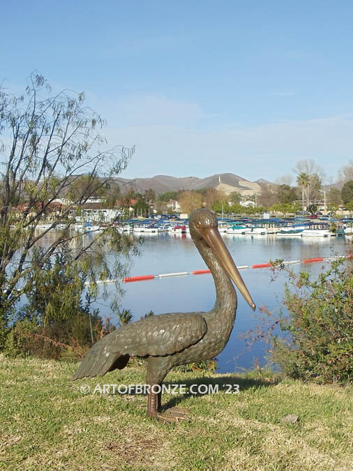 Heavenly Retreat bronze statue of resting pelican standing and looking for fish