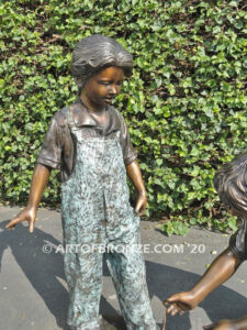 Helping Hand bronze statue of boy kneeling down and helping girl tie her shoelace