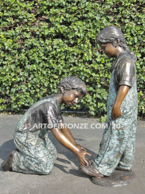 Helping Hand bronze statue of boy kneeling down and helping girl tie her shoelace