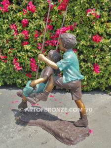 Higher & Higher outdoor bronze sculpture of boy pushing girl on swing