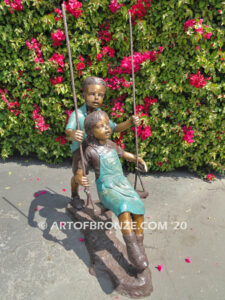 Higher & Higher outdoor bronze sculpture of boy pushing girl on swing