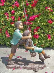 Higher & Higher outdoor bronze sculpture of boy pushing girl on swing