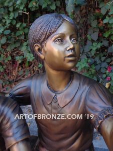 Loving Attention garden sculpture of kids sitting on rocks holding a dove in each hand