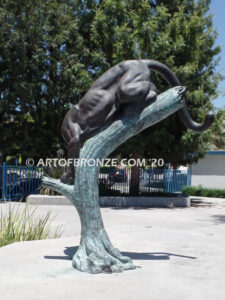 Bronze sculpture of mountain lion crouching on tree branch