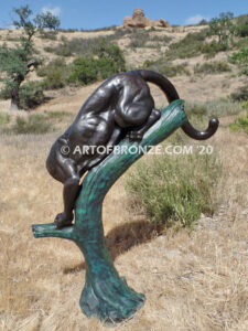 Bronze statue of mountain lion crouching on tree branch