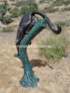 Bronze statue of mountain lion crouching on tree branch