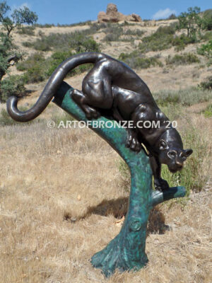 Bronze statue of mountain lion crouching on tree branch