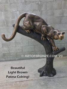 Bronze statue of mountain lion crouching on tree branch