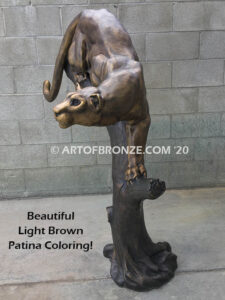 Bronze statue of mountain lion crouching on tree branch