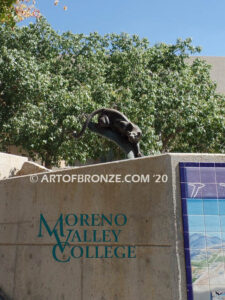 Bronze sculpture of mountain lion crouching on tree branch