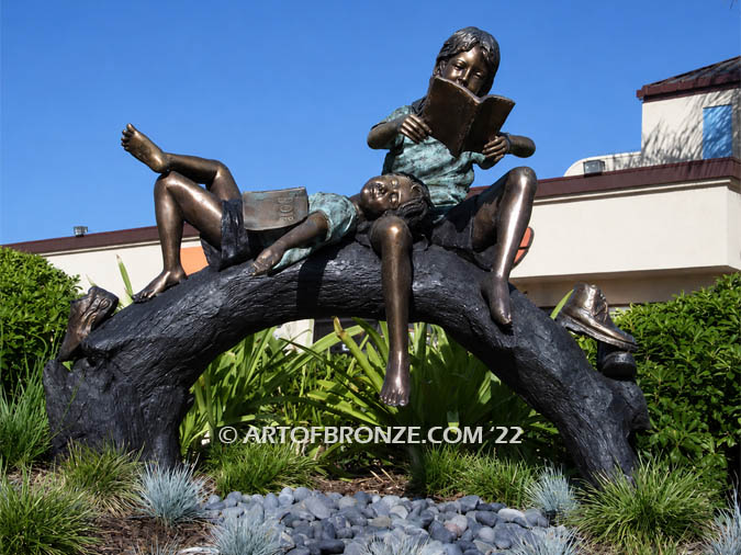 Natures Balance sculpture of girls reading and relaxing on bronze log